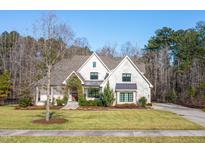 Stunning two-story home with a manicured lawn and mature landscaping on a sunny day at 5040 Shakori Trl, Chapel Hill, NC 27707