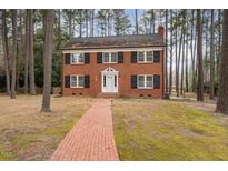 Charming two-story brick home with black shutters and a brick walkway through a tree-filled lot at 636 Palmer Dr, Sanford, NC 27330