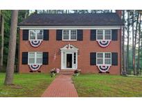 Charming brick two-story home featuring black shutters, brick walkway and decorative patriotic bunting at 636 Palmer Dr, Sanford, NC 27330