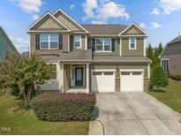 Charming two-story home with a manicured lawn, attached garage, and a mix of brick and siding at 1021 Traditions Meadow Dr, Wake Forest, NC 27587
