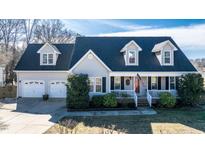 Charming single-Gathering home featuring a manicured lawn, two-car garage, and inviting front porch with American flag at 105 Glasgow Dr, Clayton, NC 27520