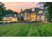 Stunning stone home with a well-manicured lawn and professionally landscaped front yard at sunset at 1801 Oatlands Ct, Wake Forest, NC 27587