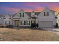 Charming two-story home featuring beige siding, green shutters, and a manicured lawn in a suburban neighborhood at 32 Colson Dr, Garner, NC 27529