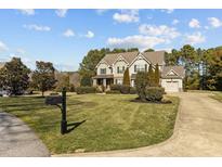 Charming two-story home featuring a well-manicured lawn, mature trees, and an attached two-car garage at 690 Hawthorne Pl, Creedmoor, NC 27522