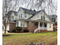 Charming brick and siding home featuring a covered porch and well-maintained landscaping at 7710 Astoria Pl, Raleigh, NC 27612
