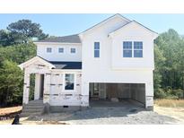 Two-story home showcasing a bright white exterior and an attached two-car garage awaiting finishing touches at 212 Fast Pitch Ln, Four Oaks, NC 27524
