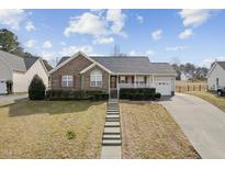 Charming one-story brick home featuring a well-manicured lawn and a cozy front porch at 2574 Primrose Ln, Creedmoor, NC 27522