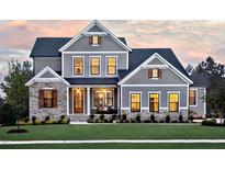 Beautiful two-story home with stone and gray siding, manicured lawn and landscaping, at dusk at 292 Choice Trl, Pittsboro, NC 27312