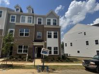A charming brick townhome showcasing a modern facade with gray accents and well-maintained landscaping at 324 Chesapeak Commons St # 143, Garner, NC 27529