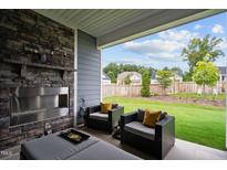 Relaxing covered patio with stone fireplace and backyard view at 3528 Olive Glen Dr, Apex, NC 27502