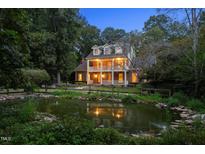 Beautiful two-story brick home with double balconies overlooking a serene pond at twilight at 1017 Holly Creek Ln, Chapel Hill, NC 27516