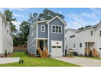 Charming two-story home with a blue exterior, white trim, front-facing garage and a well-manicured lawn at 1211 Chaney Rd, Raleigh, NC 27606