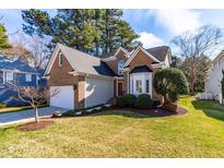 Charming brick home featuring an attached garage, manicured lawn, and mature trees for added curb appeal at 2909 Hawtree Dr, Raleigh, NC 27613