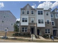 Beautiful three-story townhome with a brick facade and manicured landscaping and a small yard at 336 Chesapeak Commons St # 140, Garner, NC 27529