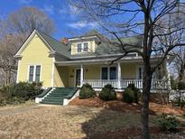 Charming yellow two-story home featuring a welcoming front porch with white columns and a green roof at 531 N Main St, Graham, NC 27253