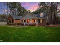 Charming brick home with welcoming front porch and manicured lawn, nestled among mature trees at 6709 Windchase Dr, Rocky Mount, NC 27803