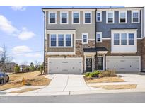 Beautiful townhome exterior featuring a stone and siding facade, two-car garage, and well-maintained landscaping at 8401 Zinc Autumn Path Path, Raleigh, NC 27615