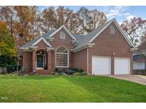 Beautiful brick home featuring an attached two-car garage and a manicured lawn with mature landscaping at 8608 Davishire Dr, Raleigh, NC 27615