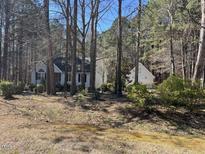 Charming single-story home with white siding, black shutters, and a lush wooded surrounding at 90 Wembley Ct, Youngsville, NC 27596