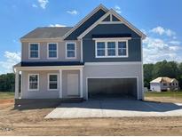 Charming two-story home with blue and gray siding, classic architectural details, and an attached two-car garage at 108 Grove Township Way, Angier, NC 27501