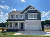 Charming two-story home features a large two car garage, black door, and manicured lawn at 108 Grove Township Way, Angier, NC 27501