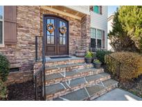 Charming front entryway featuring a stone facade, double doors with wreaths, and stone steps with iron railings at 1137 Fanning Dr, Wake Forest, NC 27587