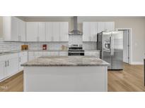Well-equipped kitchen features an island, stainless steel appliances, and white cabinets with subway tile backsplash at 1521 Chapel Hill Rd, Durham, NC 27701