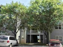 Two-story building exterior with balcony access in between, covered by trees and parked cars in front at 1911 Wolftech Ln # 303, Raleigh, NC 27603