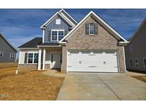 Charming two-story home with a brick facade, two-car garage, and manicured lawn on a sunny day at 2152 Pink Peony Cir # 155, Durham, NC 27703