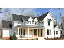 Charming white farmhouse with black roof, covered porch, and manicured landscaping at 431 Fieldstone Ln, Pittsboro, NC 27312