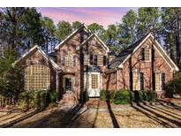 Stunning brick home featuring arched windows and dormers, surrounded by mature trees and a well-manicured lawn at 5808 Valley Mist Ct, Raleigh, NC 27613