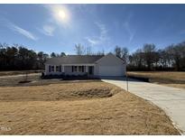Charming one-story home features a manicured lawn and inviting front porch, with an attached two-car garage at 73 Phil Jack Rd, Dunn, NC 28334