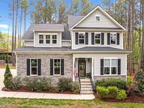 Beautiful two-story home with a stone facade, black shutters and a well-manicured front yard at 749 Bowden Rd, Chapel Hill, NC 27516
