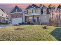 Charming two-story home featuring a stone facade, covered porch, and well-manicured lawn at 113 Palladium Ct, Elon, NC 27244