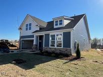 New home showing gray siding, stone accents, a two-car garage, and a well-maintained lawn at 121 Willow Cameron Way, Angier, NC 27501