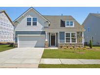 Charming, two-story home featuring a 2-car garage, landscaped yard, and a mix of stone and siding accents at 121 Willow Cameron Way, Angier, NC 27501