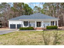 Charming single-story home boasts a welcoming porch, lush landscaping, and a two-car garage at 208 Hunting Lodge Rd, Clayton, NC 27520