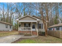 Charming home featuring a cozy front porch with brick accents and mature trees at 2513 Drexall Ave, Durham, NC 27704