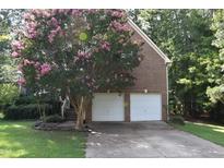 Charming brick home with a two-car garage and a beautiful pink-blossomed tree in the front yard at 5402 Whisperwood Dr, Durham, NC 27713