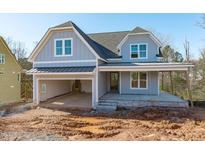 Charming two-story home featuring a welcoming front porch, attached garage, and light blue siding at 104 Pointe Park Cir, Holly Springs, NC 27540