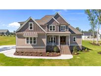 Charming two-story home featuring a manicured lawn and inviting front porch with detailed trim and updated landscaping at 165 Cotton Fields Ln # 25, Fuquay Varina, NC 27526