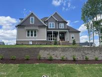 Two-story home with tan siding, gray trim, and brick foundation, set against a blue sky at 165 Cotton Fields Ln # 25, Fuquay Varina, NC 27526