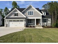 Charming two-story home with gray siding, stone accents, a manicured lawn and a three car garage at 309 Deer Tail Ln # 42, Fuquay Varina, NC 27526