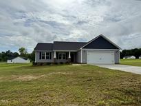 Charming single-story home featuring a two-car garage, gray siding, and a well-maintained lawn at 39 N Movado Trl, Kenly, NC 27542