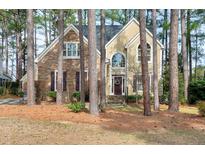 Charming two-story home with stone and siding exterior, surrounded by mature trees at 100 Burlingame Way, Cary, NC 27513