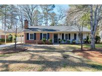 Charming single-story brick home featuring manicured landscaping and a welcoming front porch at 1405 Suterland Rd, Cary, NC 27511