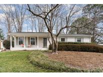 Charming single-story home featuring a covered front porch, manicured lawn, and mature landscaping at 4812 Stonehill Dr, Raleigh, NC 27609