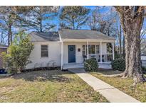 Charming white brick home with a welcoming front porch and a blue front door at 602 Quarry St, Raleigh, NC 27601