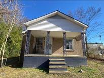 Charming brick home featuring a covered front porch with decorative iron supports and a landscaped front yard at 736 Vaughan St St, Henderson, NC 27536