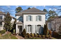 Charming two-story home with painted brick exterior, shutters, mature landscaping, and brick walkway at 809 Wayne Dr, Raleigh, NC 27608